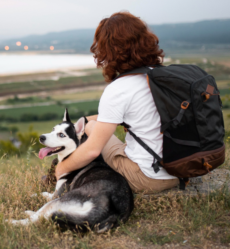 man sitting with dog in nature
